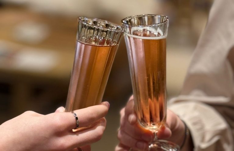 Zwei Sektgläser mit roséfarbenem Getränk stoßen an.